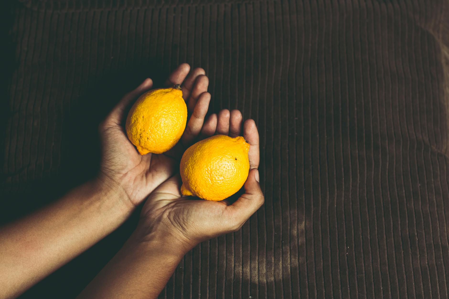 Two fresh lemons held in cupped hands, symbolizing freshness and readiness
