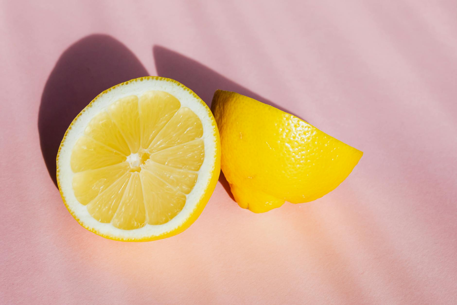 Bright lemons on a pink background in natural sunlight, symbolizing fresh perspective and ease