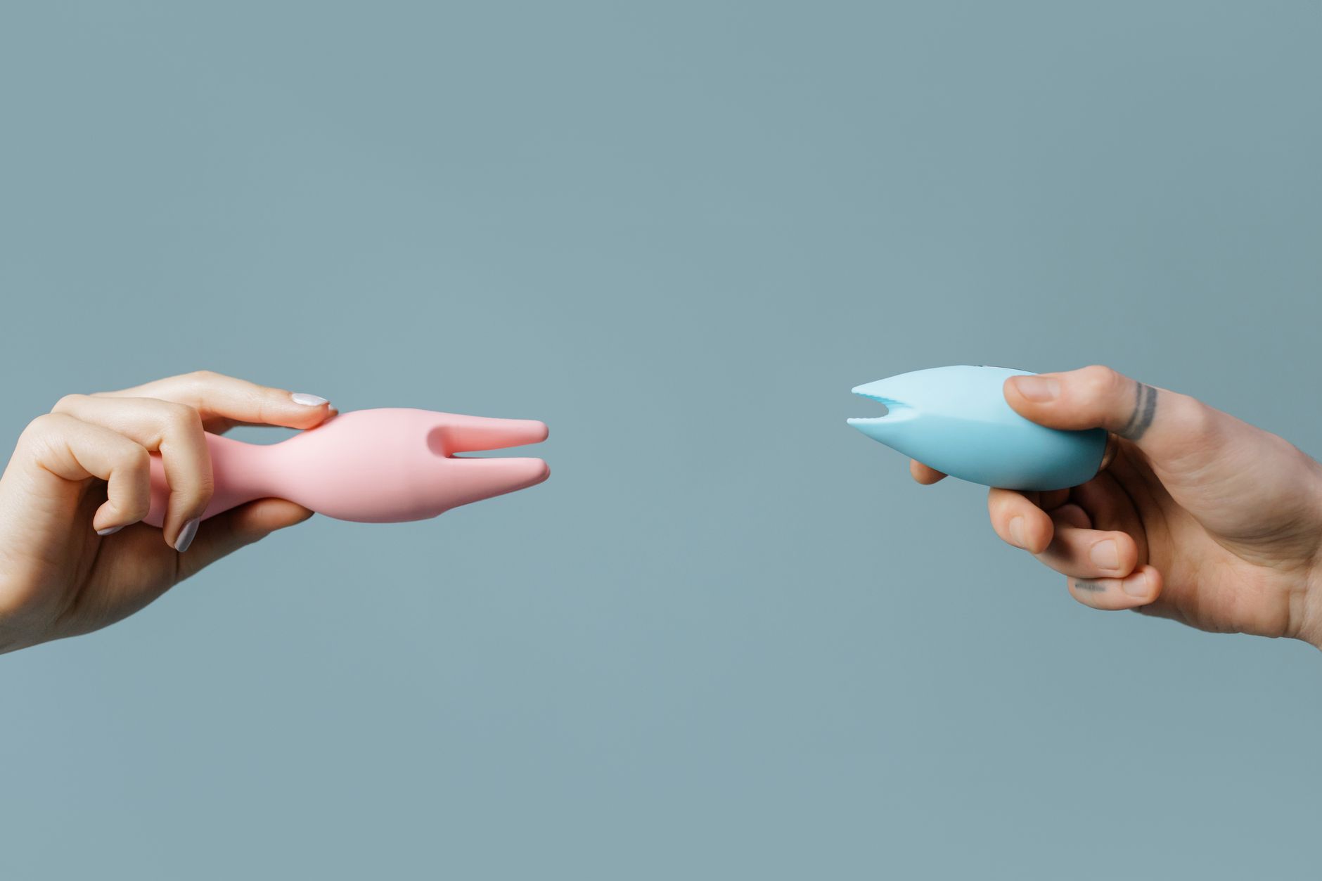 Primer plano de manos sosteniendo un vibrador azul oscuro contra un fondo púrpura, mostrando autoconocimiento e intimidad