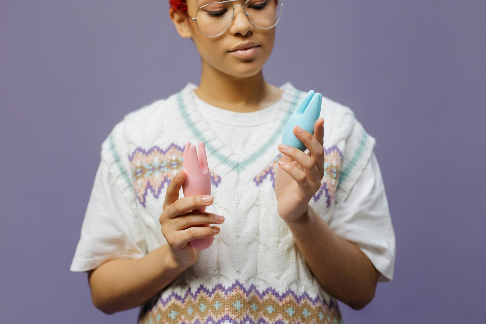 Woman holding blue and pink silicone vibrators in a contemplative moment of self-discovery.