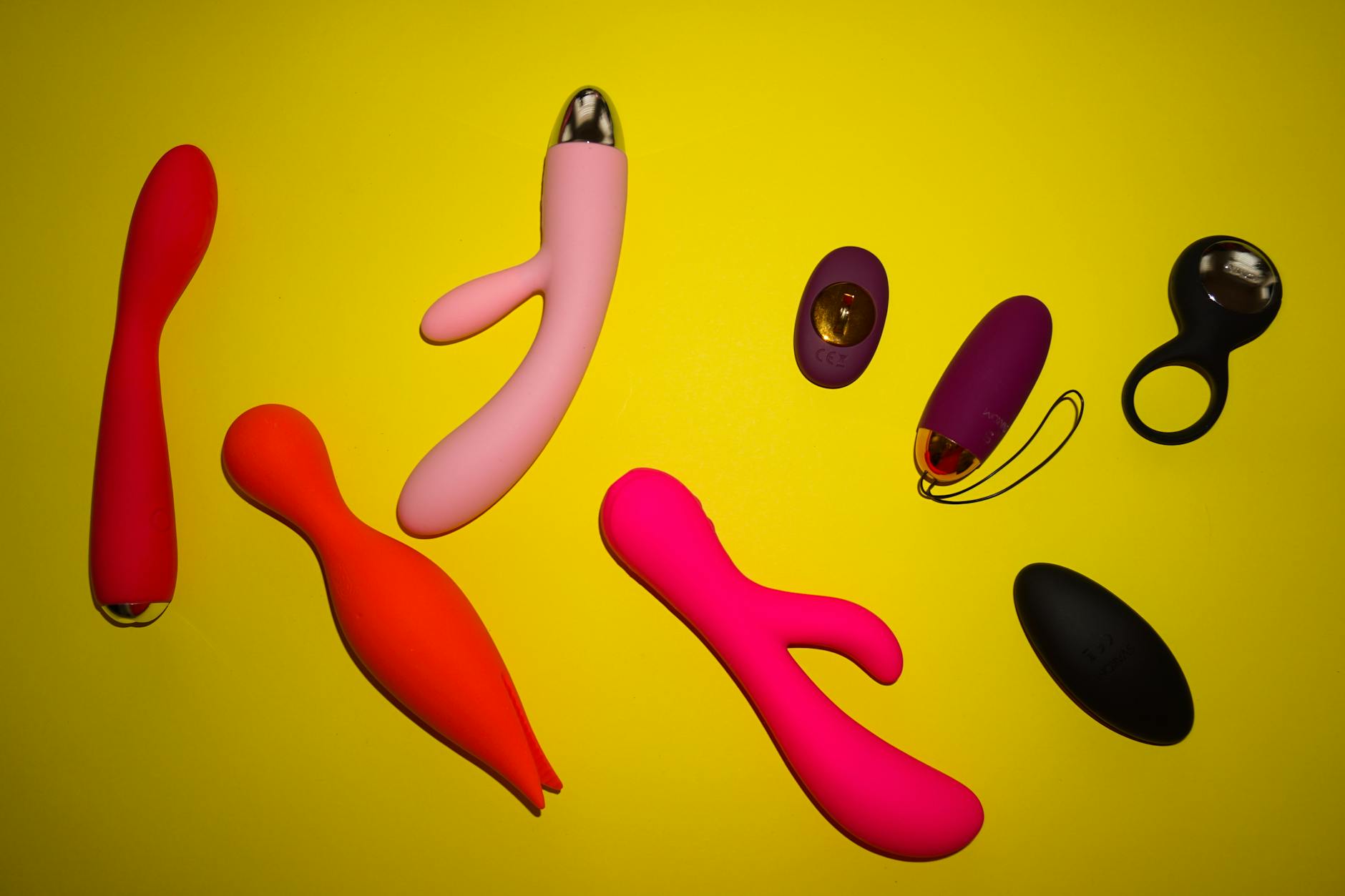 Colorful vibrators arranged on bright yellow surface, showing variety and design