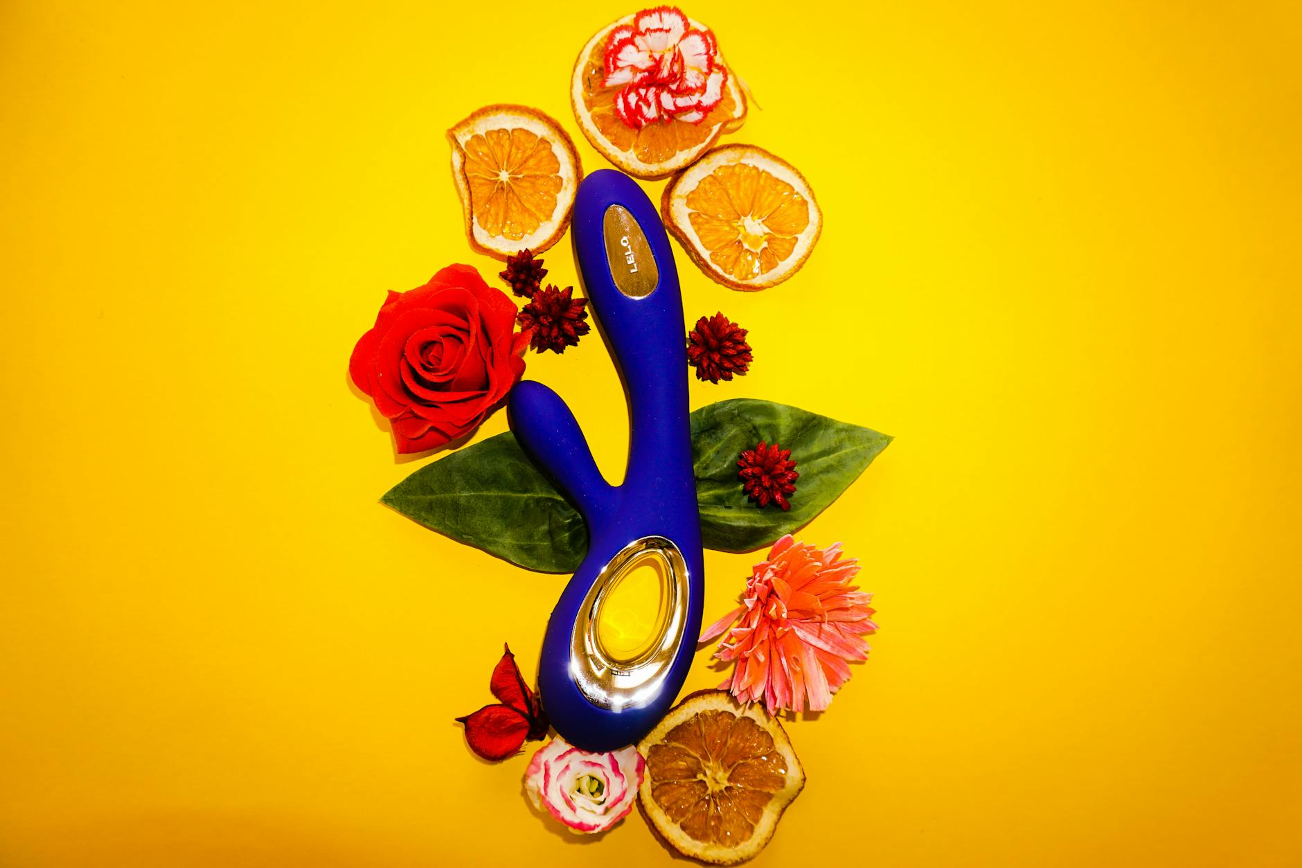 Blue lemon vibrator surrounded by flowers and citrus on a yellow background