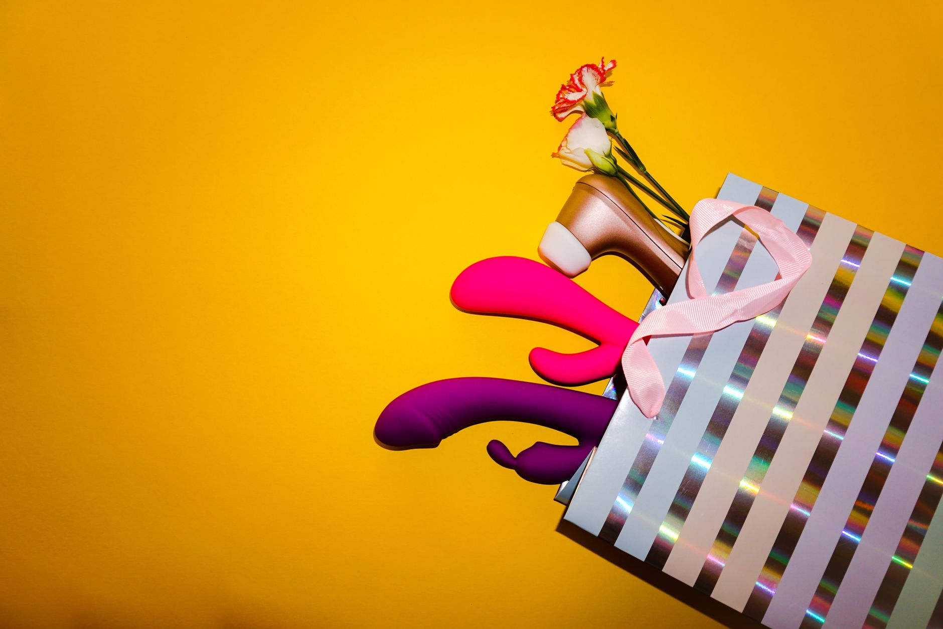 Woman thoughtfully holding a blue and pink vibrator, considering her approach to pleasure.