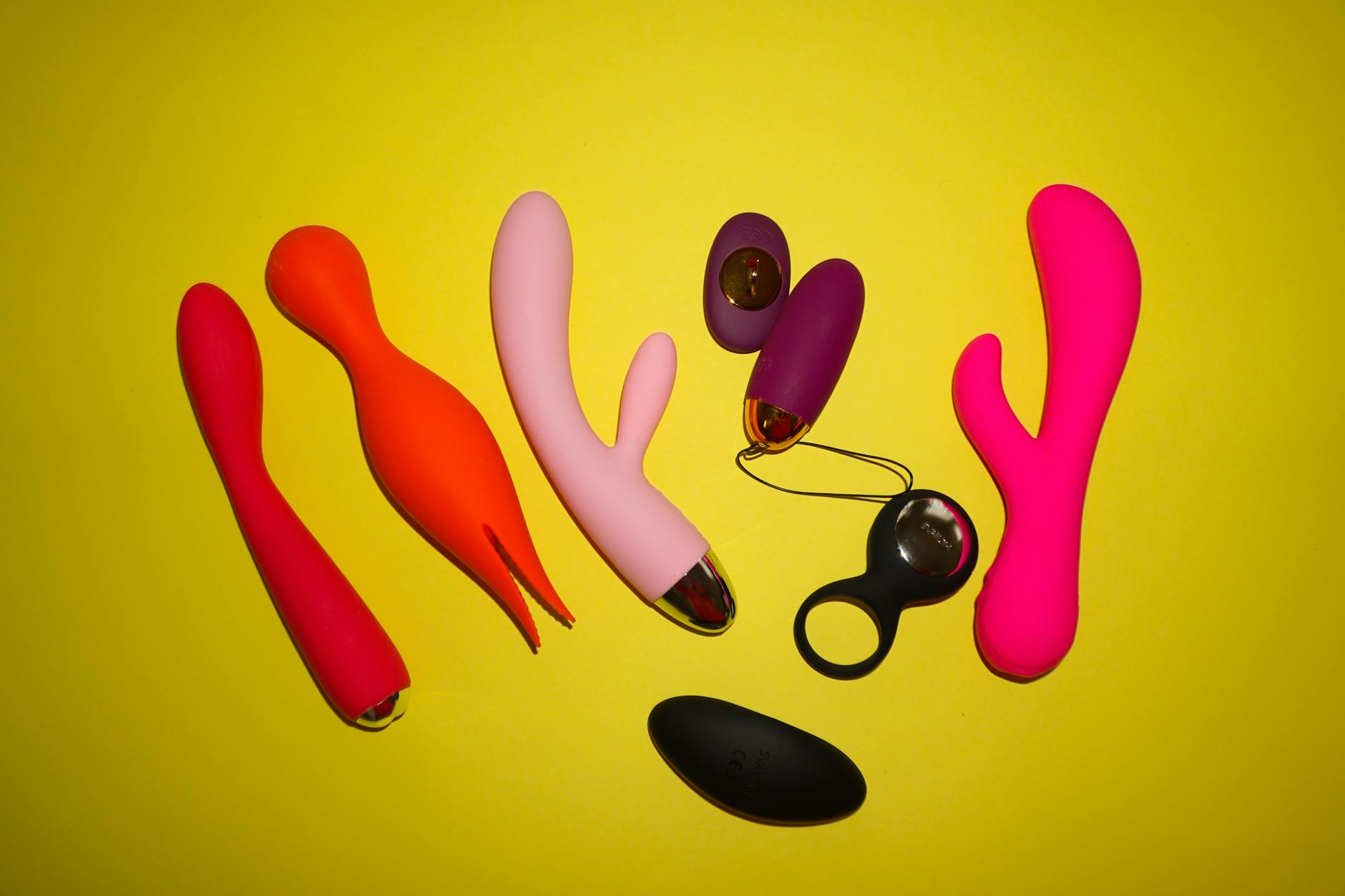 Hands reaching toward colorful vibrators on a table, symbolizing choice and connection
